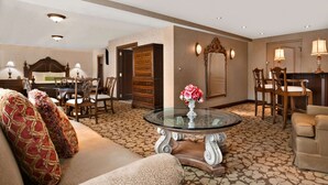 A spacious living room with a round glass coffee table, a sofa, and a dining area with wooden chairs and a table. - Hilton Garden Inn Rochester/Pittsford (Pittsford)