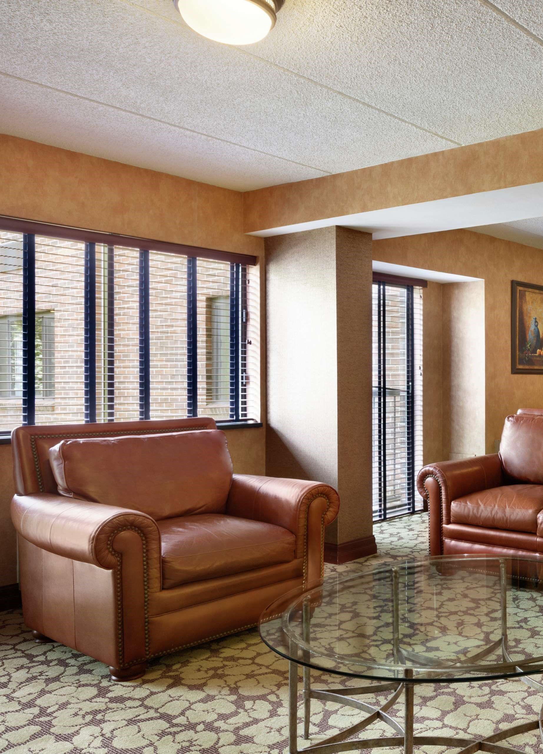 A room with two leather armchairs, a glass coffee table, and a patterned carpet.