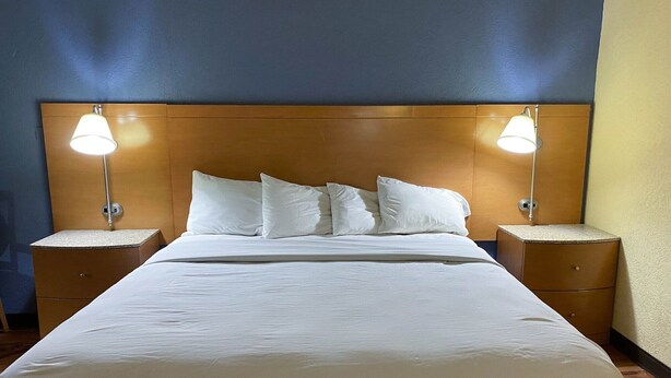 Una habitación de hotel con una cama grande, dos mesitas de noche y dos lámparas de pared.