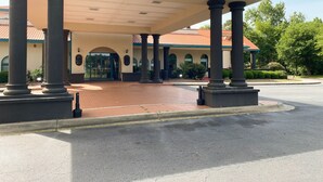 Un edificio con un acceso cubierto, columnas y techo de tejas.