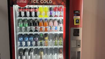 A Coca-Cola branded ice cold beverage vending machine with a variety of drinks and a payment keypad.