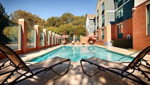 A swimming pool with lounge chairs and a brick building in the background. - Best Western Plus Roswell / Alpharetta (Roswell)