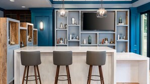 A modern kitchen with a central island, bar stools, and built-in shelves with decorative items. - Hampton Inn Savannah-Historic District (Savannah)