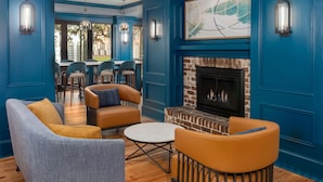 A modern lounge area with blue walls, a brick fireplace, and comfortable seating. - Hampton Inn Savannah-Historic District (Savannah)