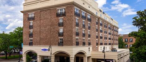 A multi-story hotel with a brick facade, multiple balconies, and a clear sky.