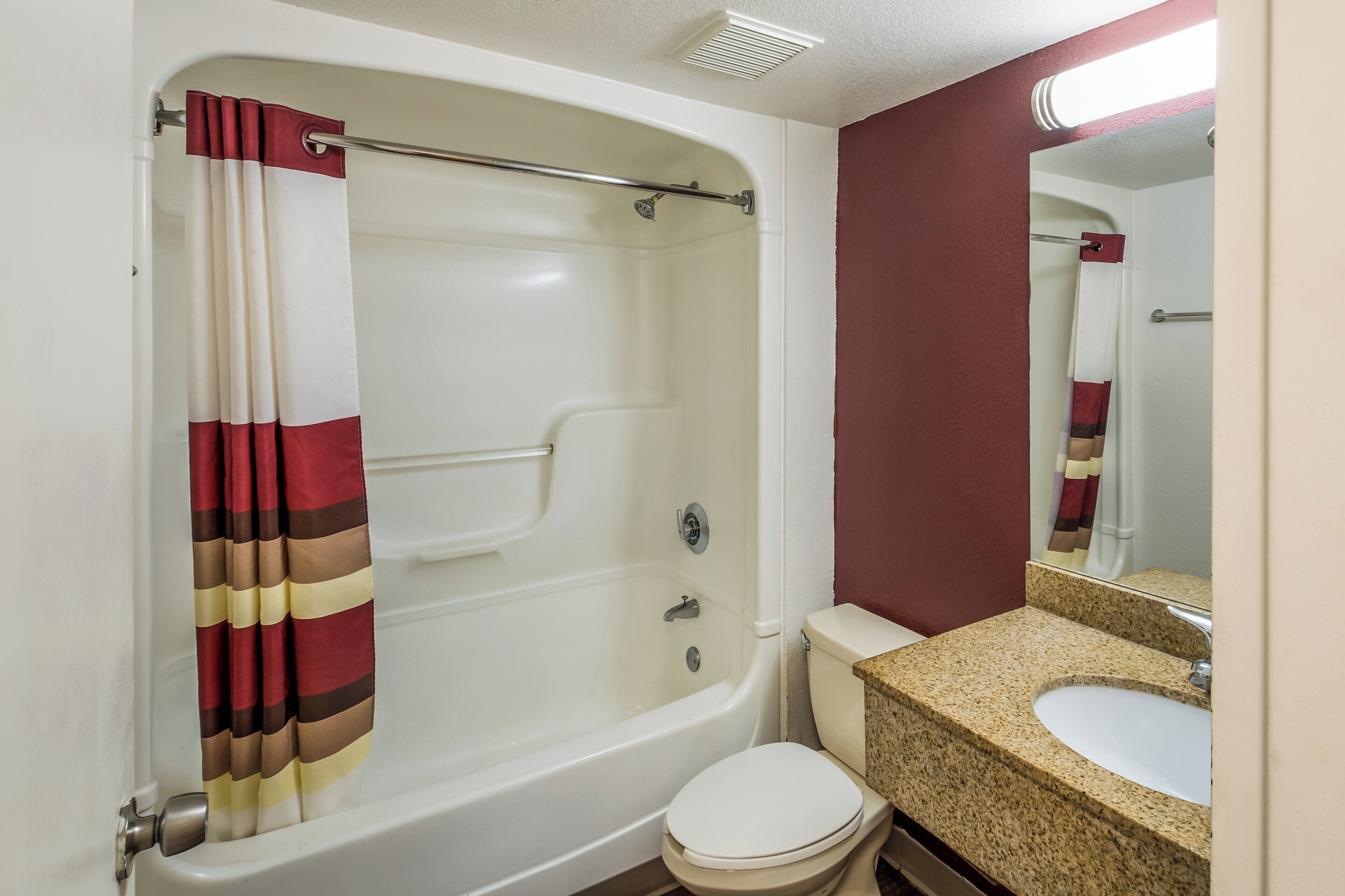 A bathroom with a bathtub, toilet, sink, and mirror.