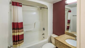 A bathroom with a bathtub, toilet, sink, and mirror.