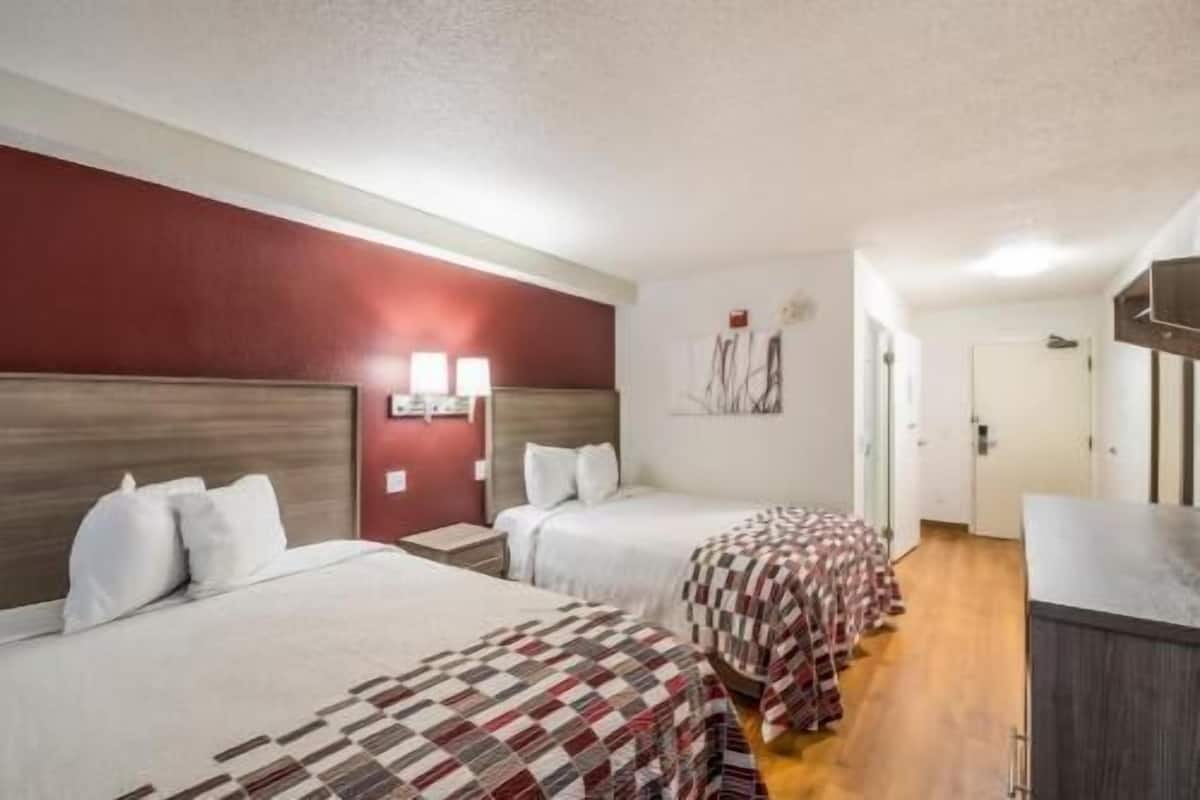 Una habitación de hotel con dos camas, un escritorio y un armario.