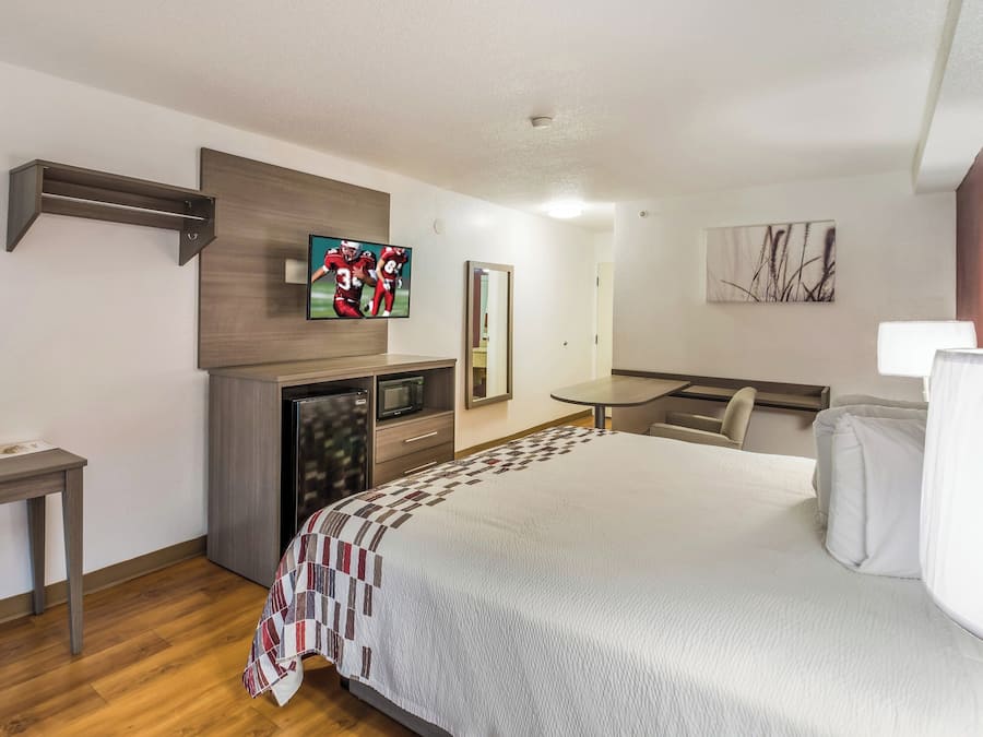 Une chambre d’hôtel équipée d’un lit, d’un bureau, d’une télévision, d’un four à micro-ondes et d’un miroir.