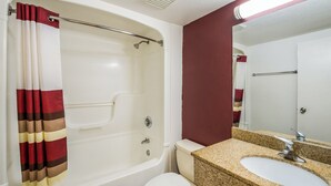 A bathroom with a bathtub, toilet, sink, and mirror. - Red Roof Inn Rochester – Airport (Rochester)
