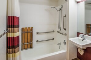 A bathroom with a bathtub, a shower, a handrail, a grab bar, a sink, and a mirror. - Red Roof Inn Rochester – Airport (Rochester)