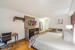 A hotel room with a bed, a desk, a chair, a television, and a mirror. - Red Roof Inn Rochester – Airport (Rochester)