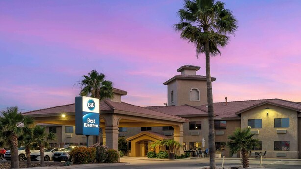 Un hotel Best Western con un ingresso centrale, palme e cielo sereno.