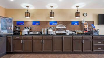 A breakfast bar with various food items and appliances, including a coffee machine and a fruit display.