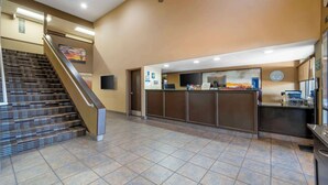 Un'area di accoglienza con un banco reception, una scala e un orologio a parete.