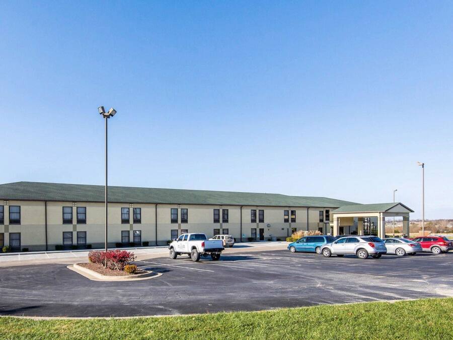 Un hotel con aparcamiento, varios coches y un edificio con techo verde.