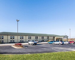 A hotel with a parking lot, several cars, and a building with a green roof.