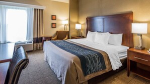 A hotel room with a large bed, two bedside tables with lamps, a desk, and a chair.