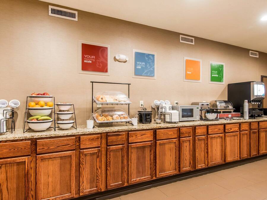 Un área de desayuno de hotel con un mostrador de autoservicio, diversos alimentos y una estación de café.
