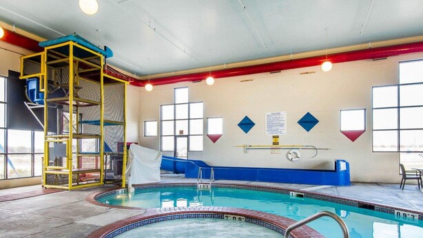 A swimming pool with a hot tub, a ladder, and a slide.