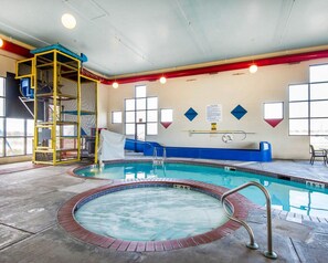 A swimming pool with a hot tub, a ladder, and a slide.