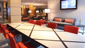 A modern conference room with a long table, red chairs, and a sofa. - Lindner Hotel Frankfurt Hochst, part of JdV by Hyatt (Frankfurt)