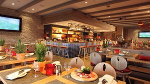 A restaurant with multiple dining tables, chairs, and a bar area with shelves of bottles. - Lindner Hotel Frankfurt Hochst, part of JdV by Hyatt (Frankfurt)