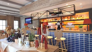 A bar area with wooden shelves, a blue-tiled wall, and a television screen. - Lindner Hotel Frankfurt Hochst, part of JdV by Hyatt (Frankfurt)