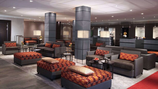 A modern hotel lobby with sofas, ottomans, and a reception desk. - Lindner Hotel Frankfurt Hochst, part of JdV by Hyatt (Frankfurt)
