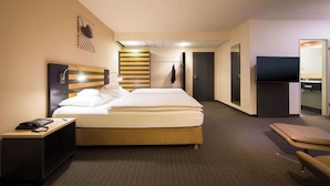 A hotel room with a bed, bedside table, lamp, and a TV. - Lindner Hotel Frankfurt Hochst, part of JdV by Hyatt (Frankfurt)