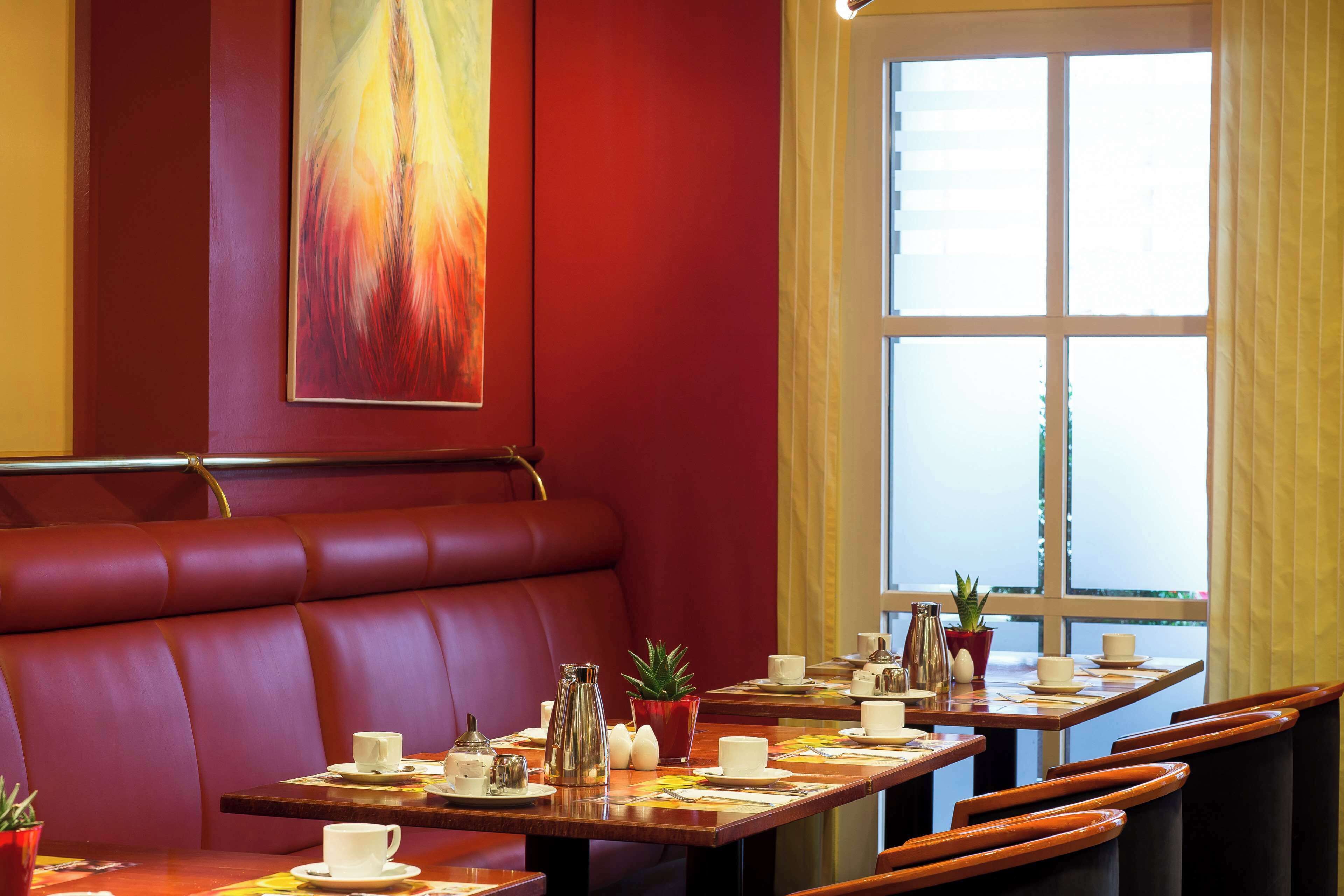 A restaurant with red leather booths, wooden tables, and a large window with a view.