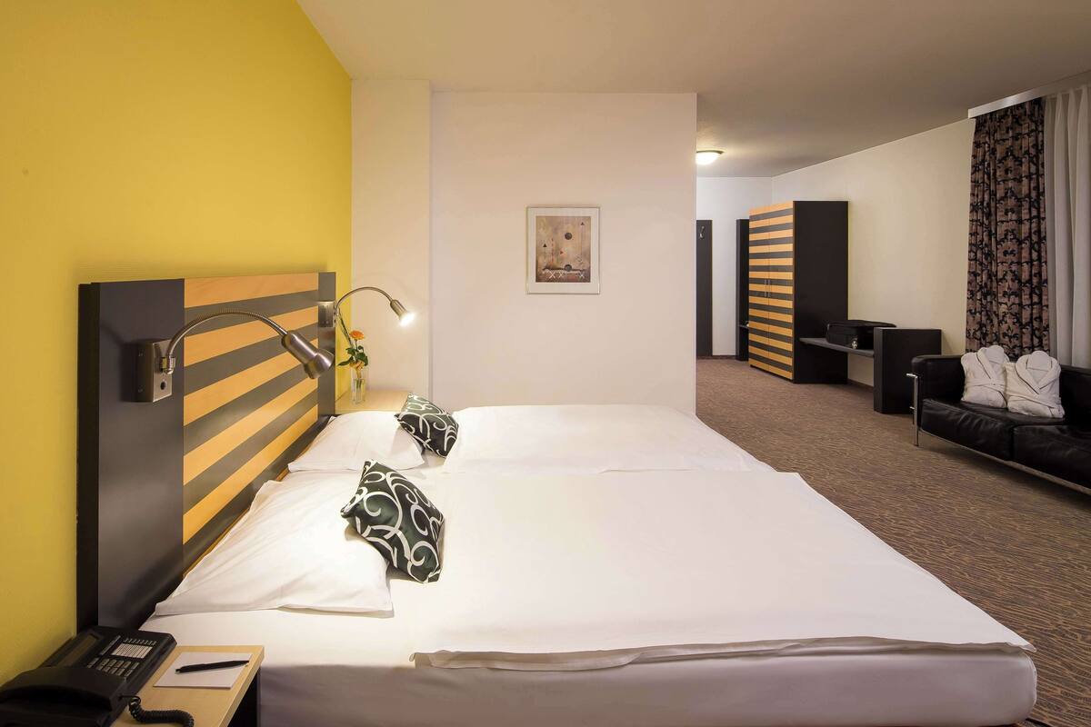 A hotel room with a large bed, a bedside telephone, a lamp, and a painting on the wall.