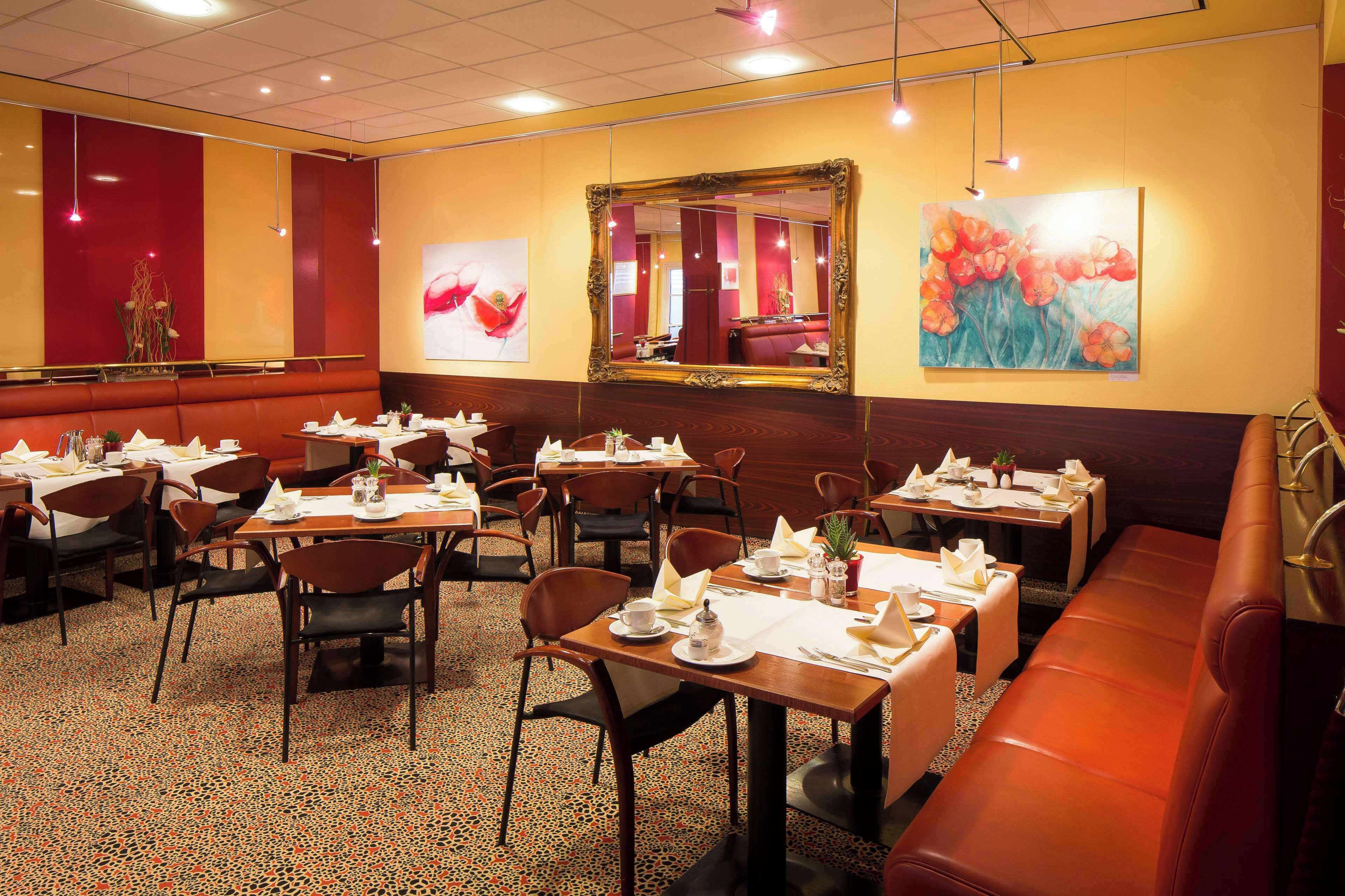 A restaurant with multiple tables and booths, each set with white tablecloths and silverware.