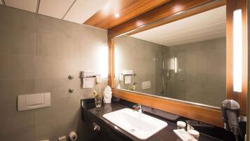 Un baño moderno con un espejo grande, un lavabo, un inodoro y una zona de ducha.