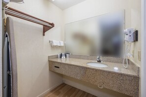 A bathroom with a granite countertop, a sink, a mirror, a towel rack, and a hairdryer on the wall.