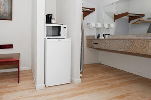 Uma cozinha compacta equipada com geladeira branca, micro-ondas e uma cadeira de madeira.