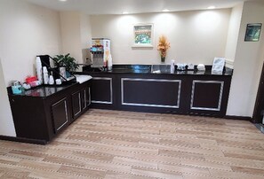 Zona de recepció amb un mostrador negre, una màquina de cafè i una planta en test.