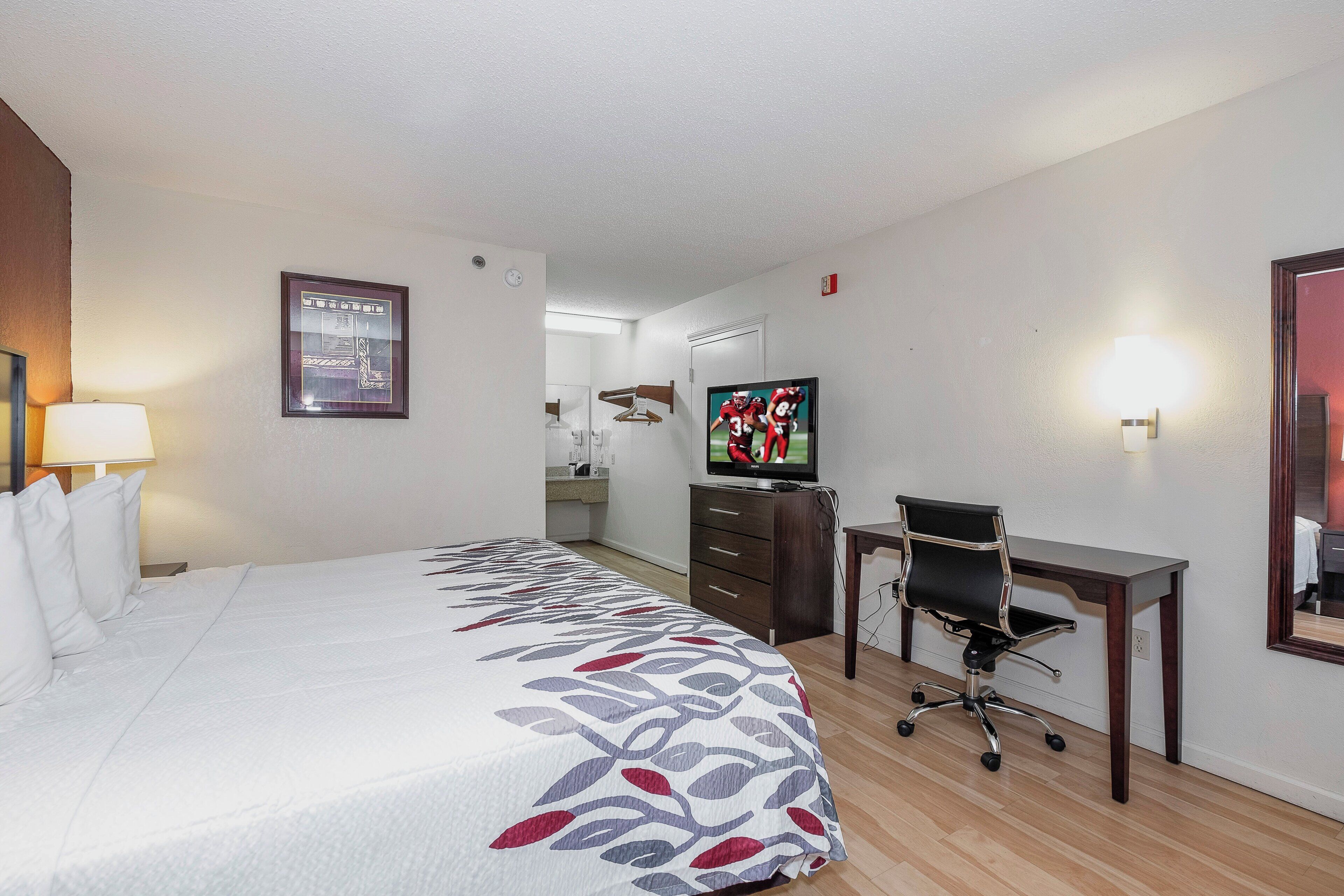 Une chambre d’hôtel avec un grand lit, un bureau, une télévision et un miroir.