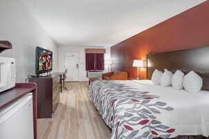 Quarto de hotel com cama, escrivaninha, televisão e micro-ondas.