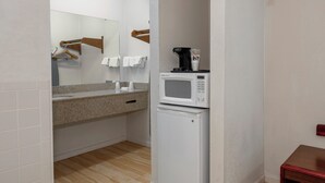 Una kitchenette compacta con microondas, un refrigerador pequeño y una encimera con cafetera.