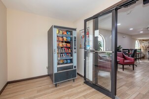 Máquina expendedora llena de aperitivos y puerta de cristal que da acceso a una habitación.