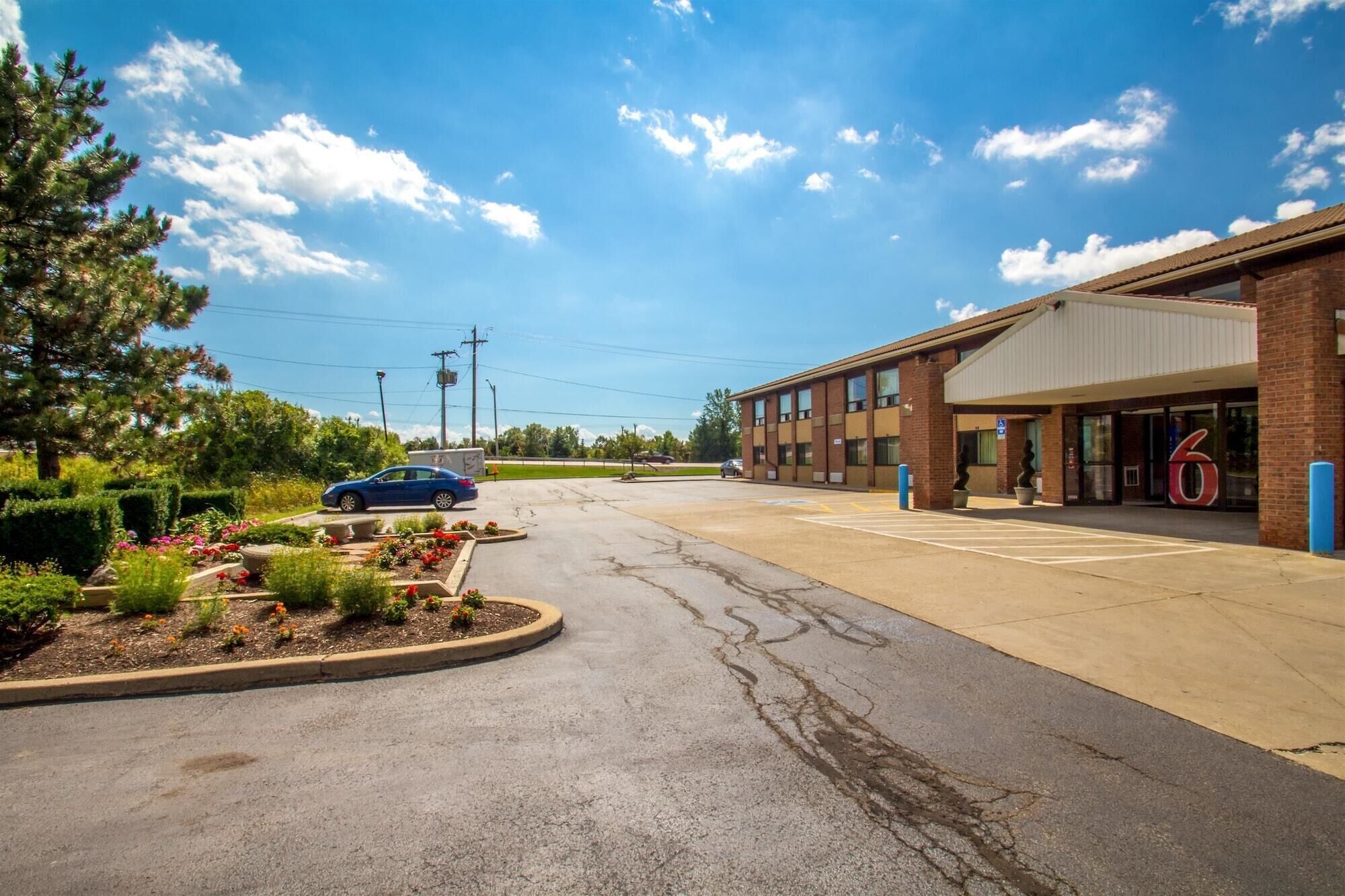 A parking lot with a building that has a large '6' sign, suggesting it might be a hotel or similar establishment.