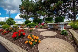 A landscaped garden with a stone pathway, benches, and various flowering plants. - Motel 6 Amherst, NY - Buffalo (Buffalo)