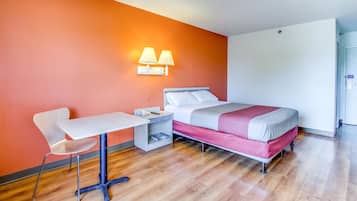 Una habitación de hotel con una cama, un escritorio y una silla.