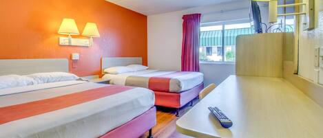Habitación de hotel con dos camas, un escritorio y una lámpara.