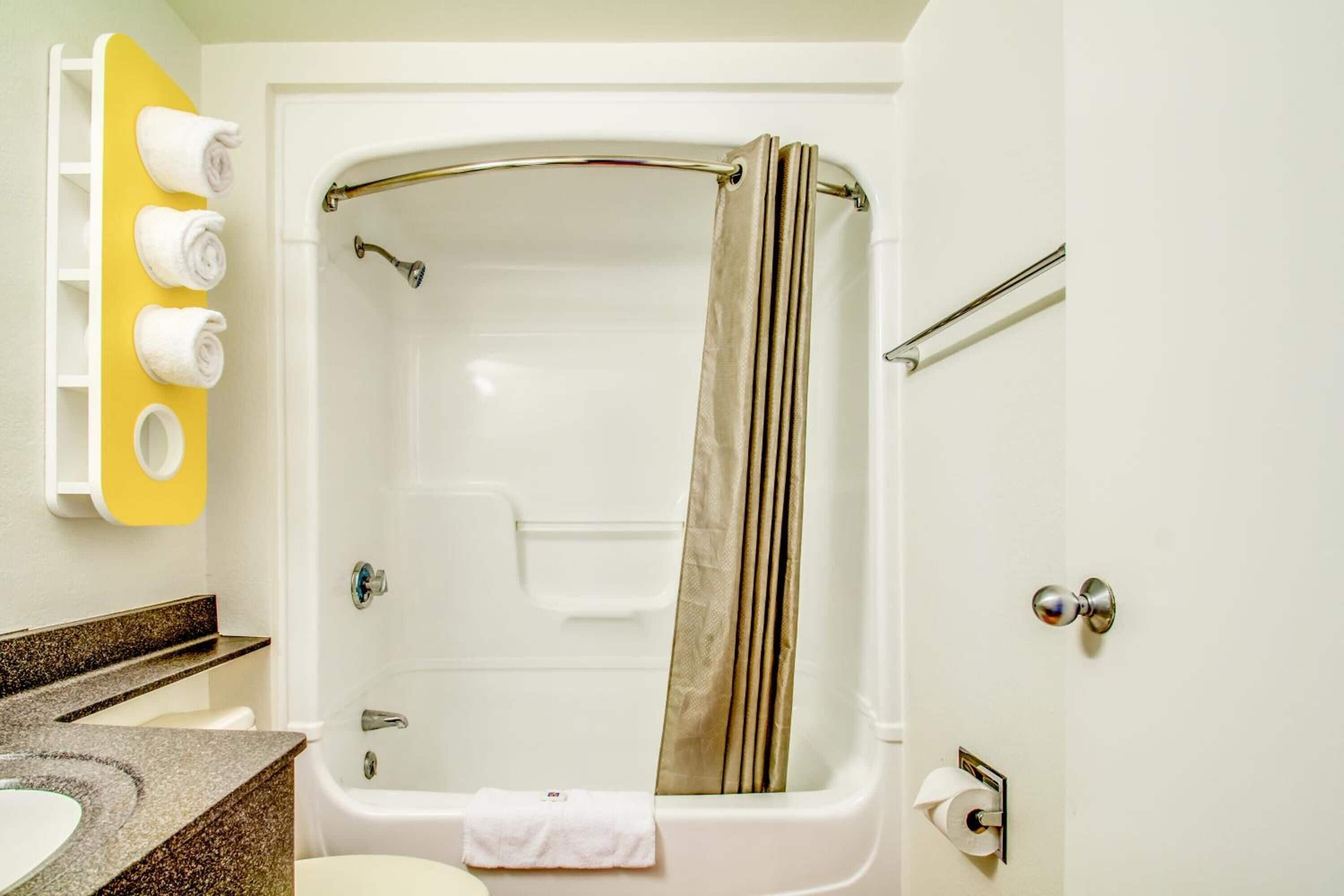 Un baño con bañera, inodoro, lavabo y toallero con toallas.