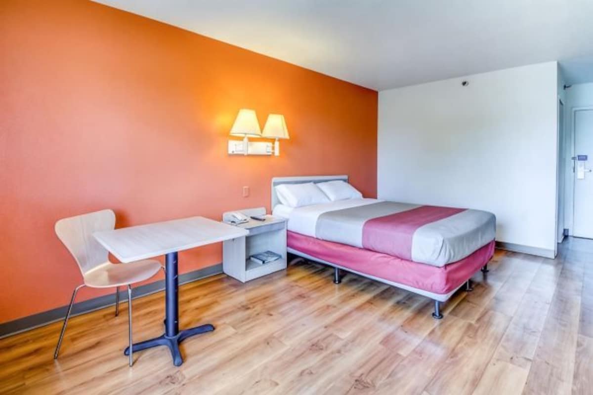 A hotel room with a bed, a desk, a chair, and a nightstand.