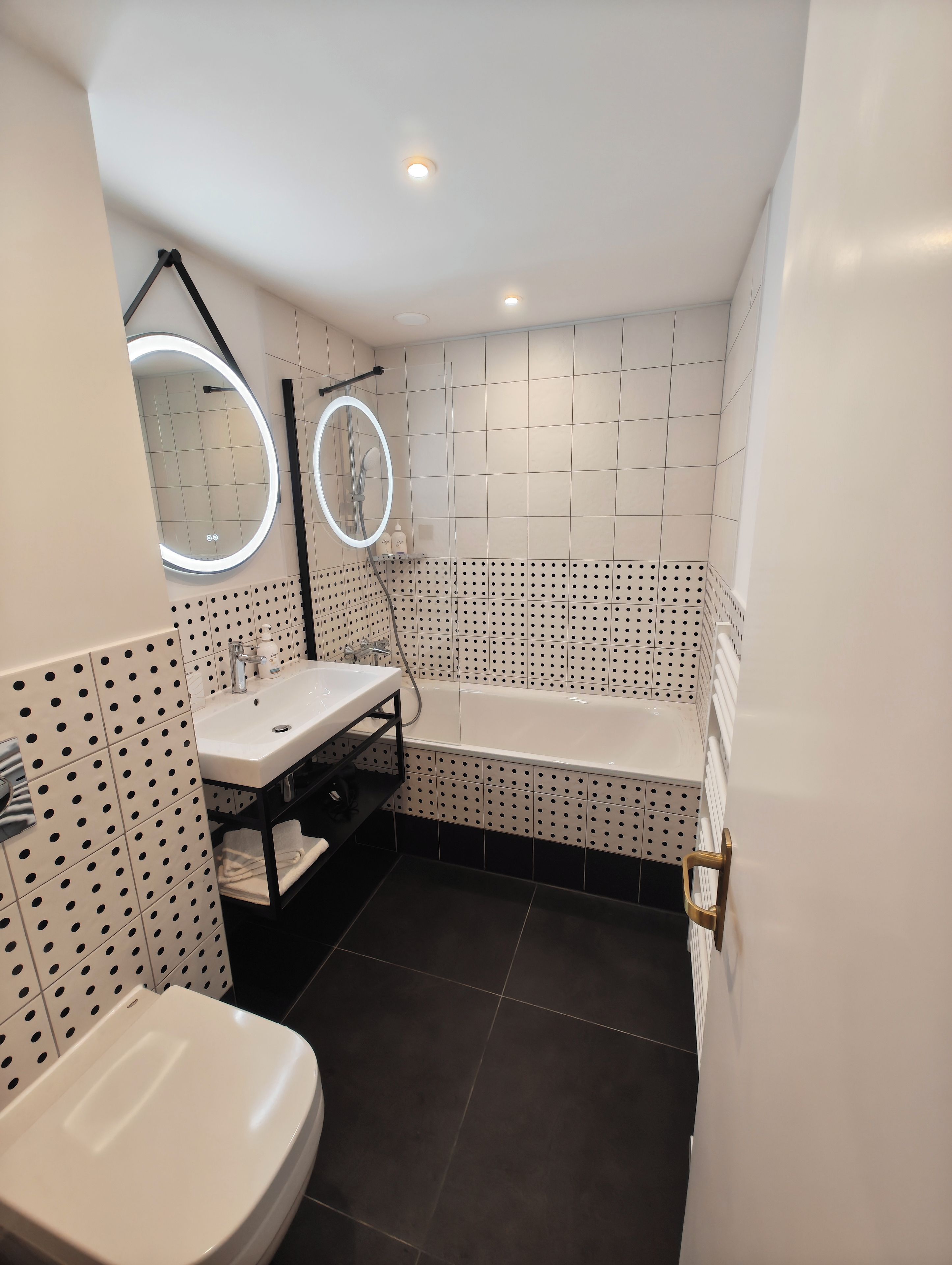 A bathroom with a white sink, a mirror, a bathtub, and a toilet.