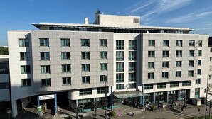 Un bâtiment moderne doté d’un toit plat, de nombreuses fenêtres et d’un espace d’entrée abrité.