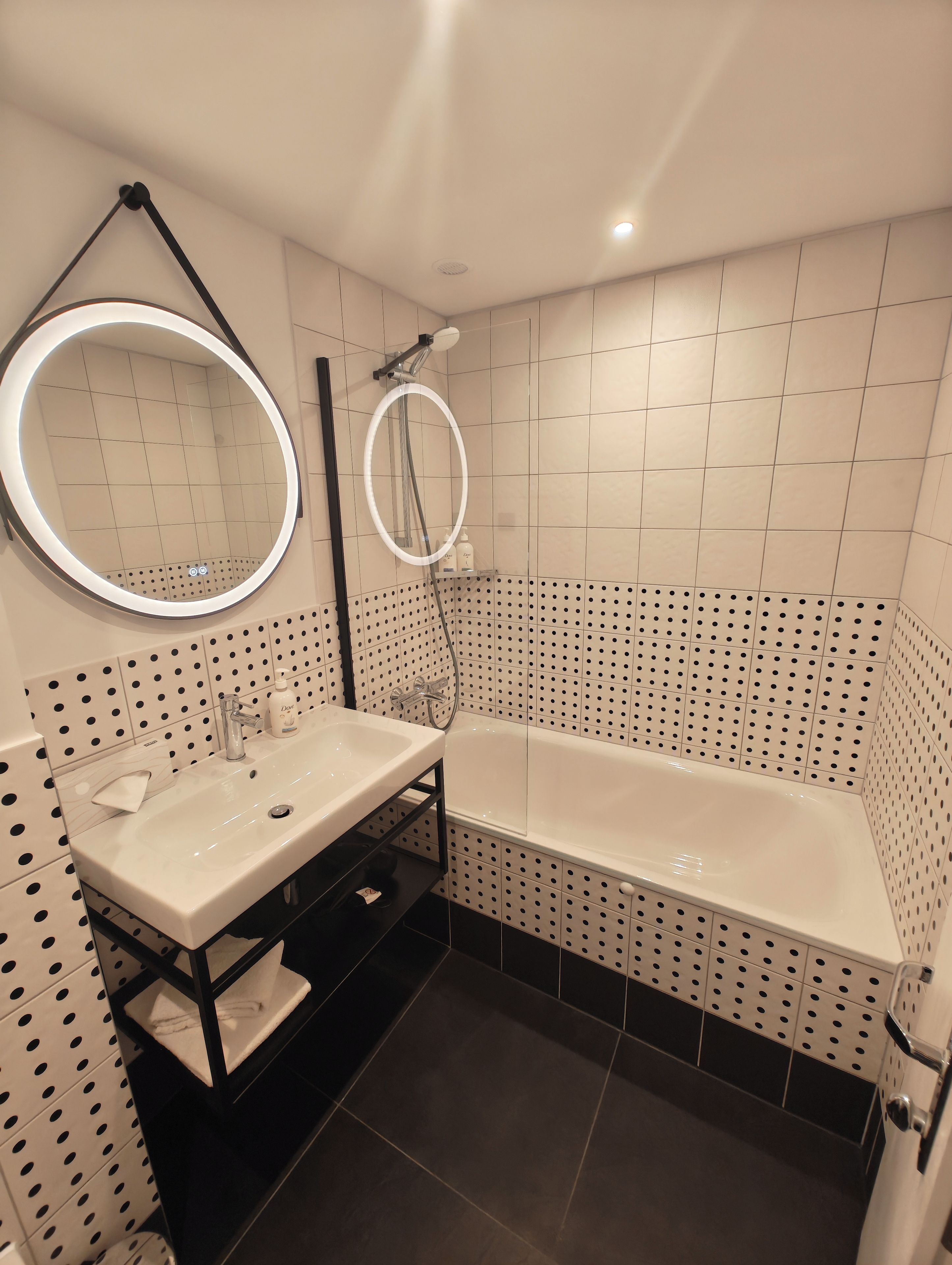 Une salle de bain moderne avec une baignoire sur pieds, un miroir rond et un meuble-lavabo à deux vasques.